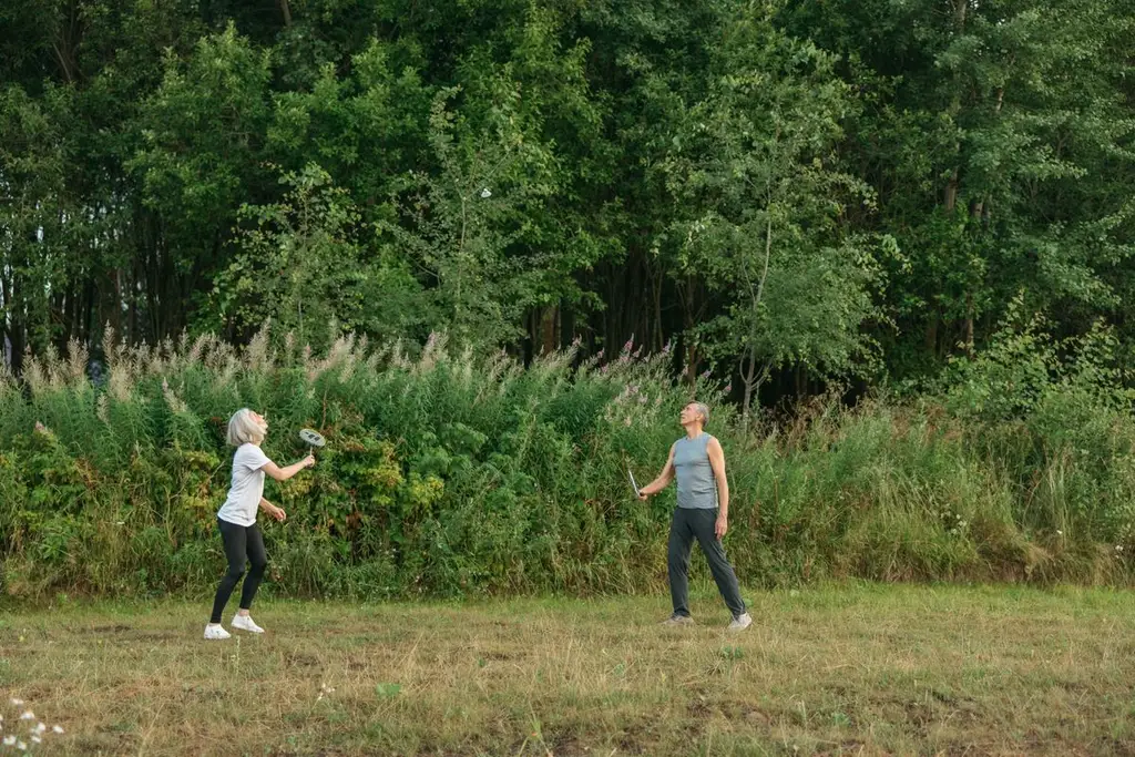 Casal de idosos ativos jogando badminton ao ar livre