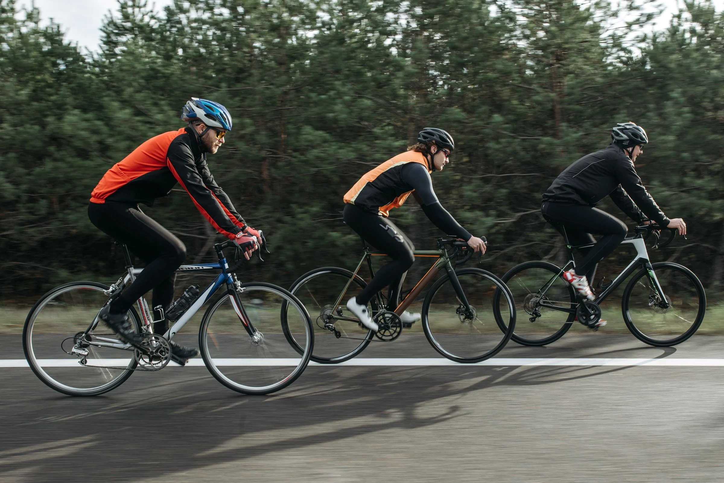 Ciclistas pedalando lado a lado numa estrada arborizada