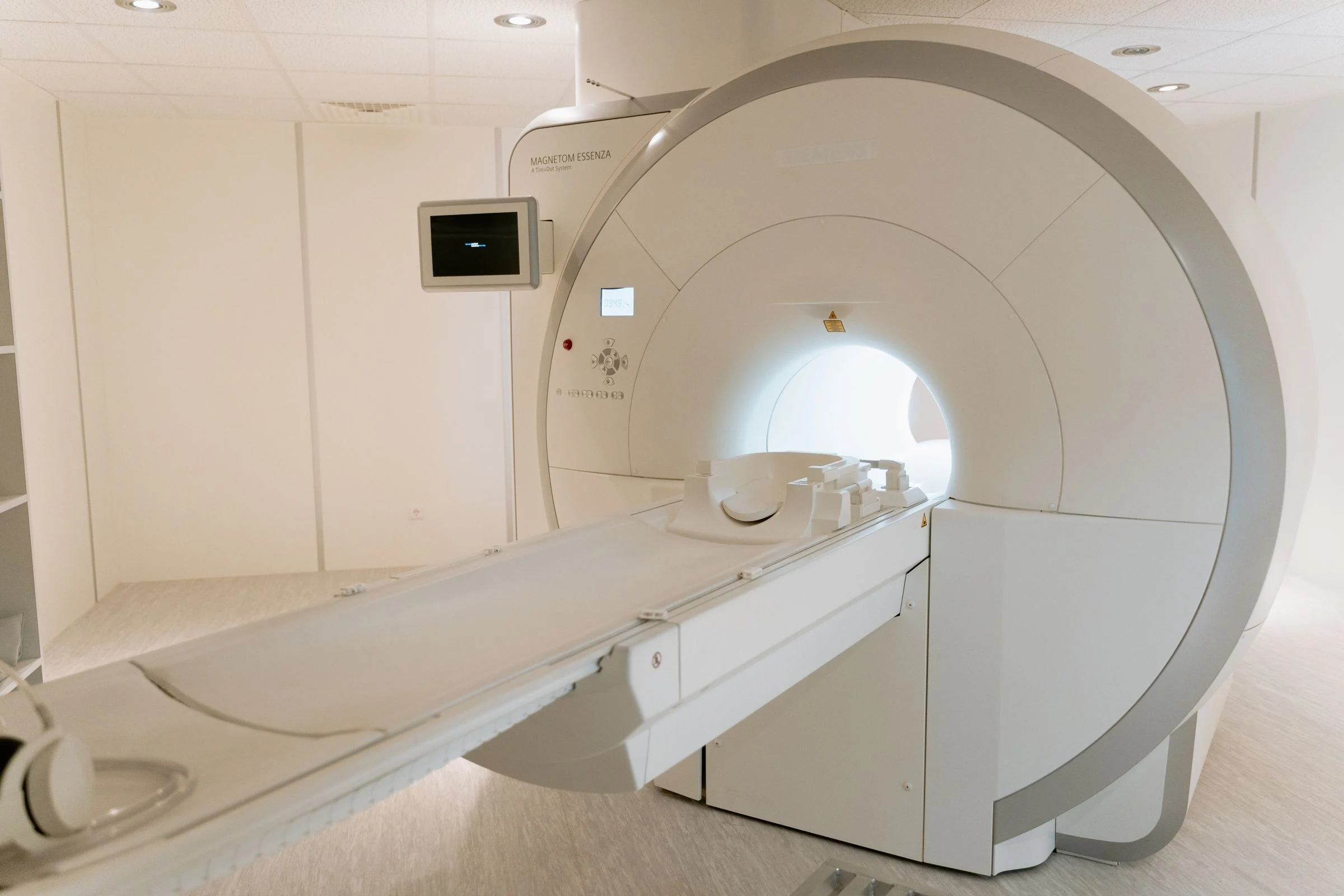 Sala moderna de ressonância magnética, com o aparelho aberto e a maca de acesso preparada